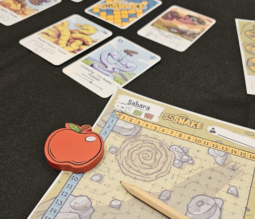 "Sssnake: Flip&Write" ist ein schnell erlerntes, außergewöhnliches Grid-Movement-Flip&Write-Spiel für 2-6 Personen ab 8 Jahren mit einer Spieldauer von 20-30 Minuten, in dem wir uns über abwechslungsreiche Karten schlängeln, die aus verschiedenen Untergründen bestehen. Dabei fressen wir Äpfel, um länger zu werden und Spezialfähigkeiten zu erlernen.